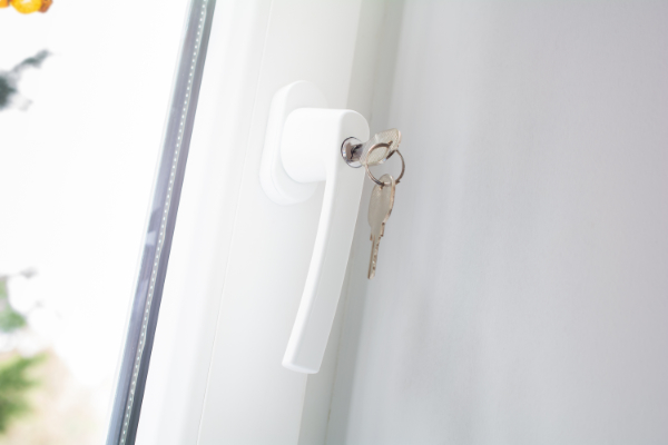 Weißer abschließbarer Fenstergriff mit steckendem Schlüssel