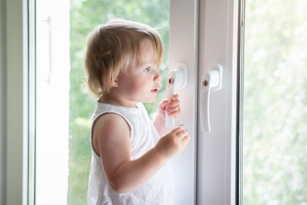 Kind am Fenster mit abschließbaren Griff als Schutz